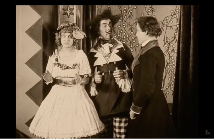 Film still from Die Puppe (The Doll, 1919): three costumed figures in an Expressionist, zigzag-patterned set.