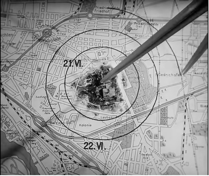 Film still from M (1931): an enormous compass inscribes concentric circles dated 21.VI. and 22.VI. on a city map, centered on a 3D miniature garden house.